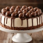 A whole no-bake Malteser Cheesecake on a white cake stand